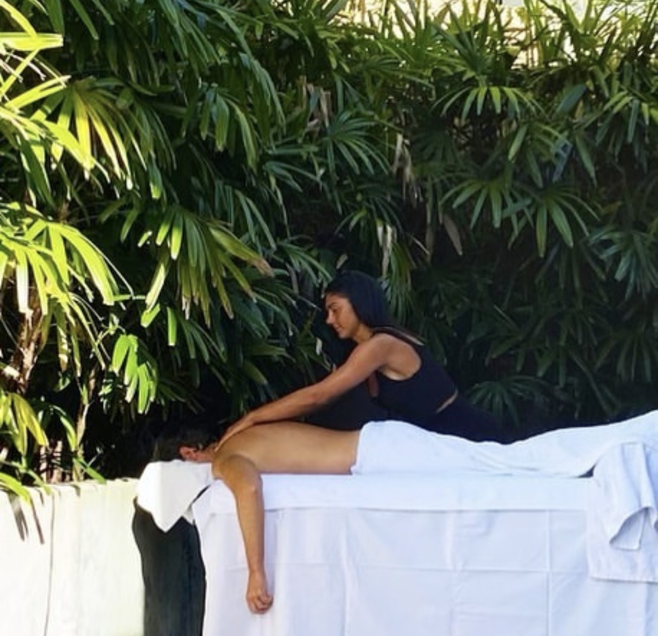 Outdoor massage treatment surrounded by lush greenery